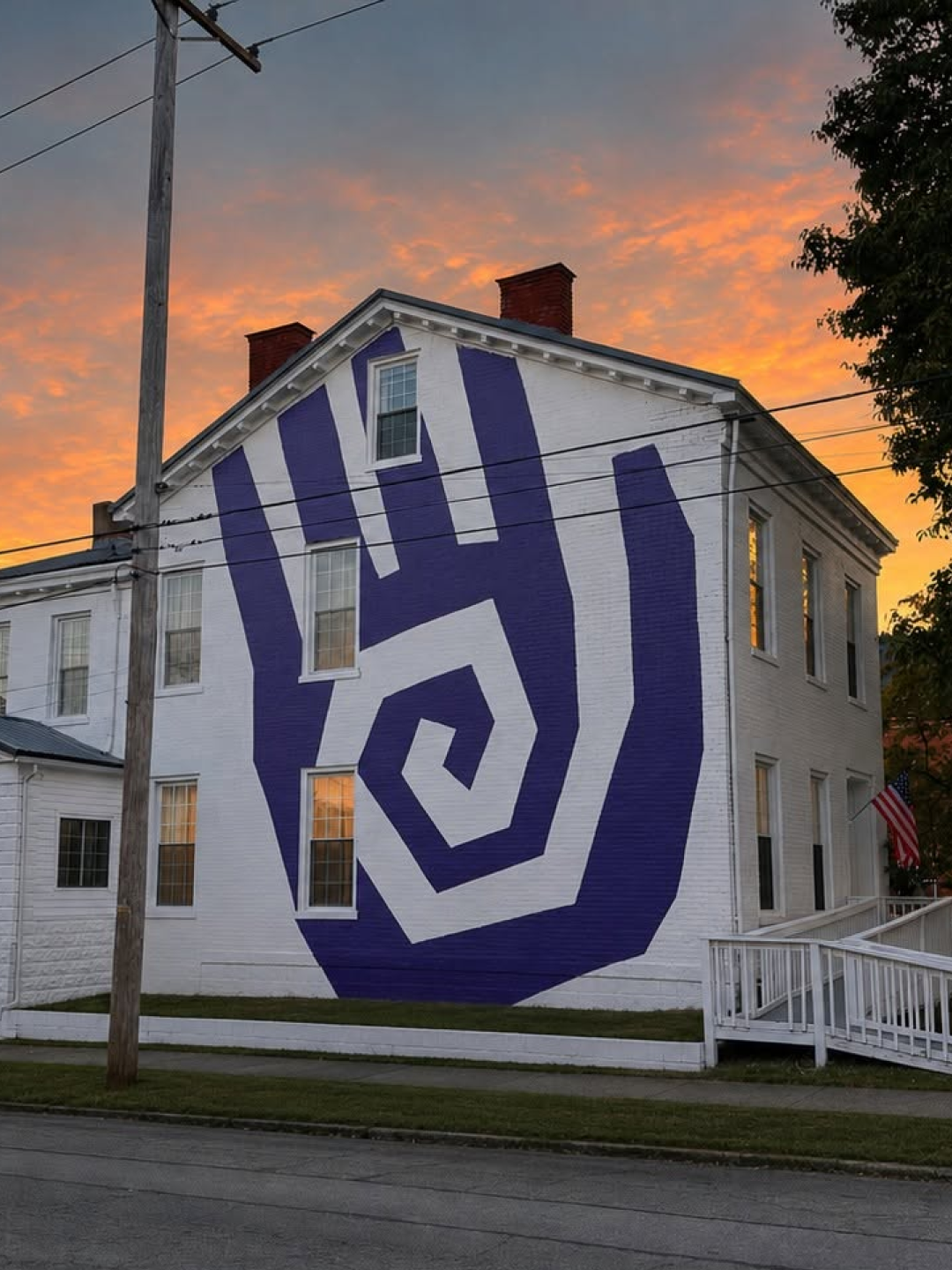 Purple Shawnee Counseling Center hand mural painted on a white building at sunset.