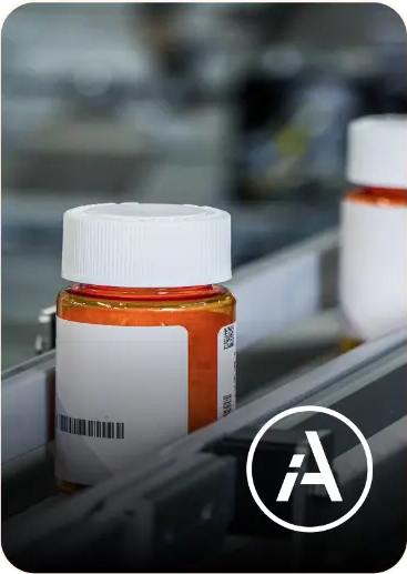 Prescription bottles moving along a pharmacy fulfillment line with an iA roundel.